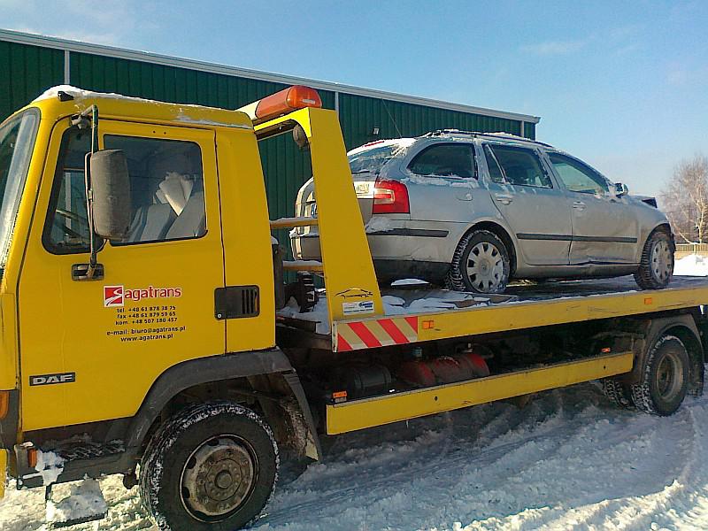 Autolaweta transportująca samochód osobowy przez zaspę śnieżną